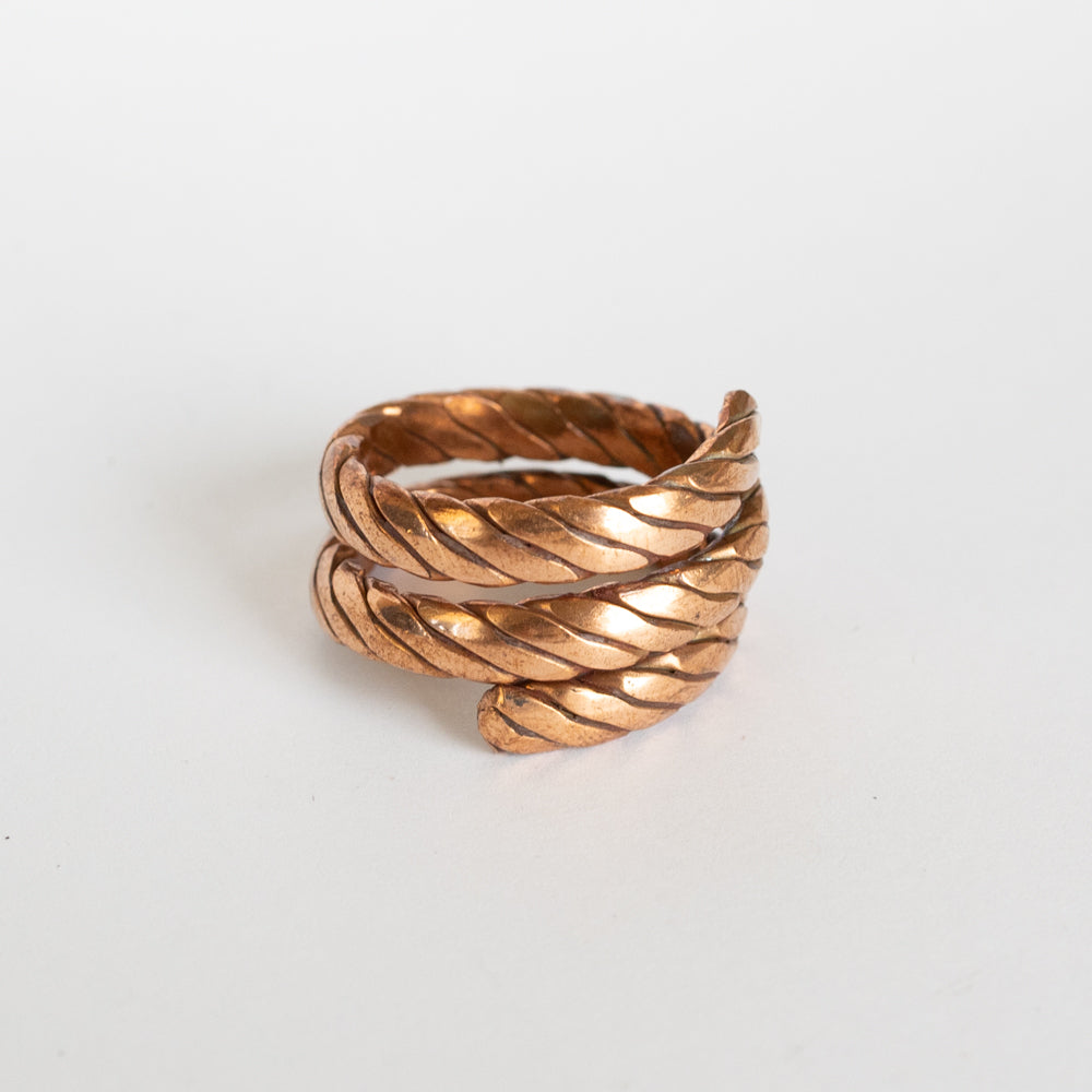 Copper twisted ring with a textured design on a white background