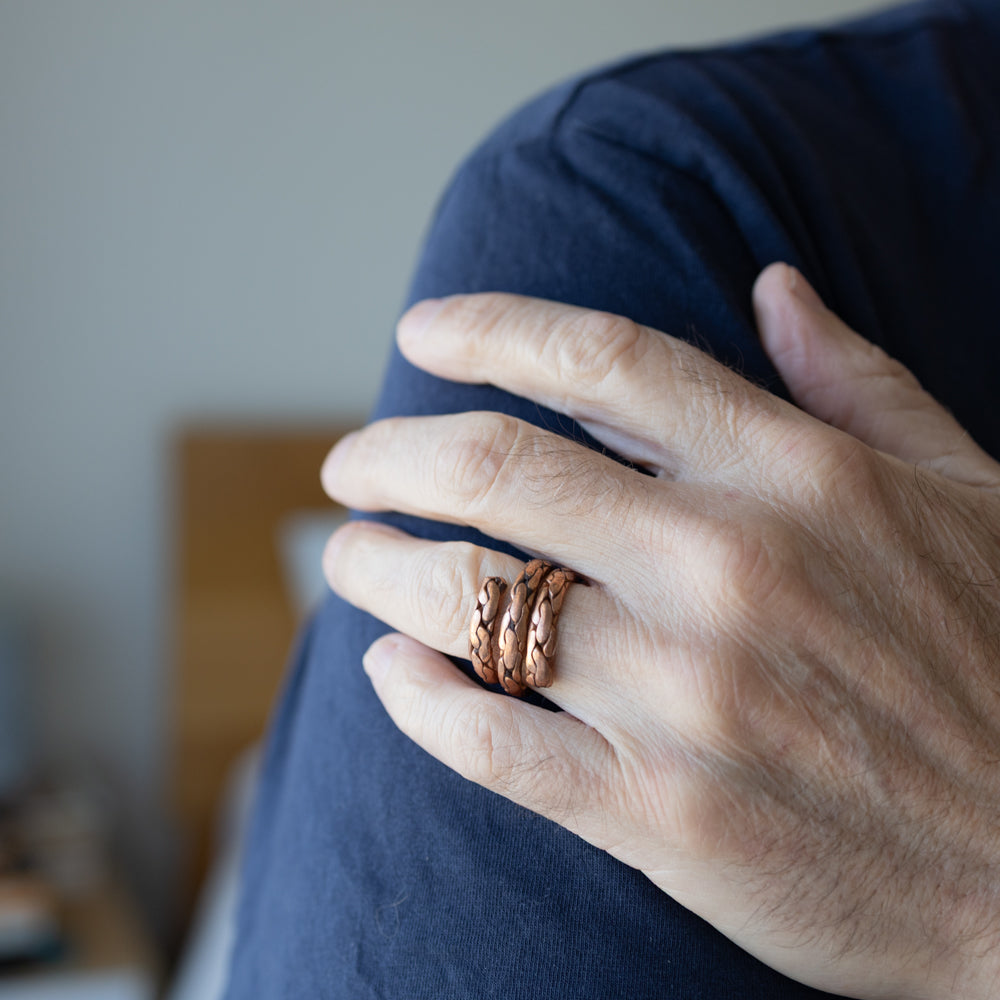 Hand wearing a copper ring on a blurred background