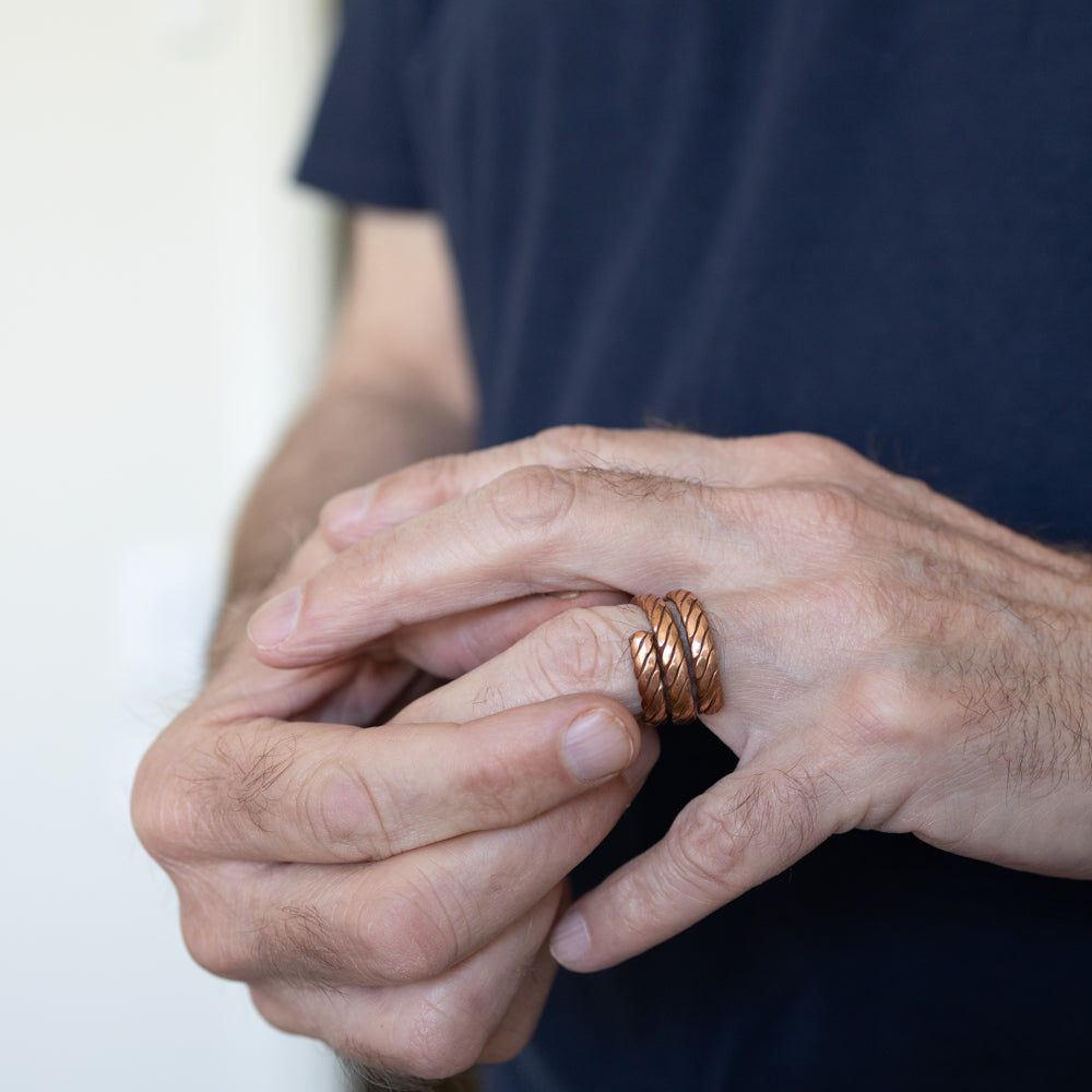 Close-up of a person's hands with a copper ring on a blurred background