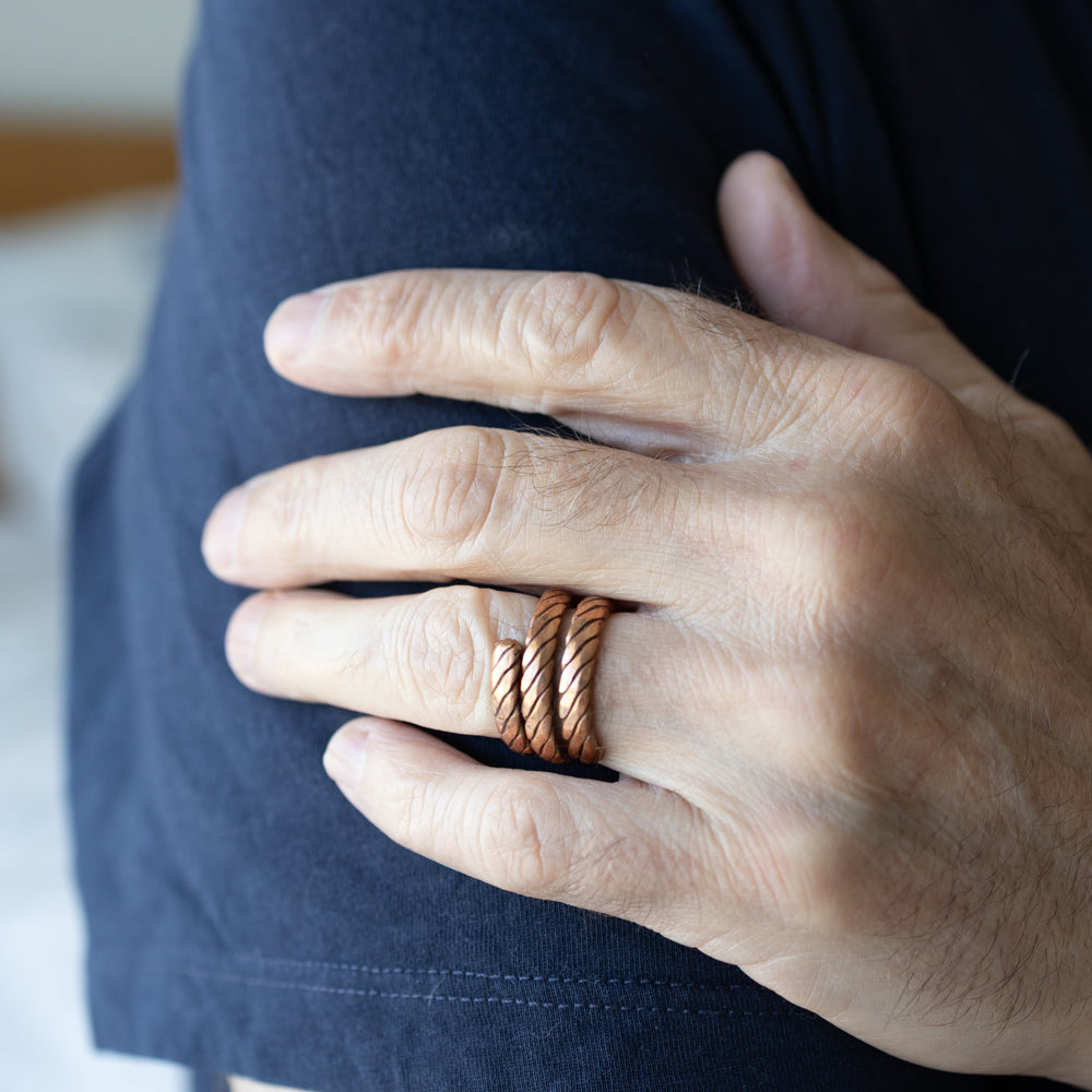 Hand wearing a copper ring with a blurred background