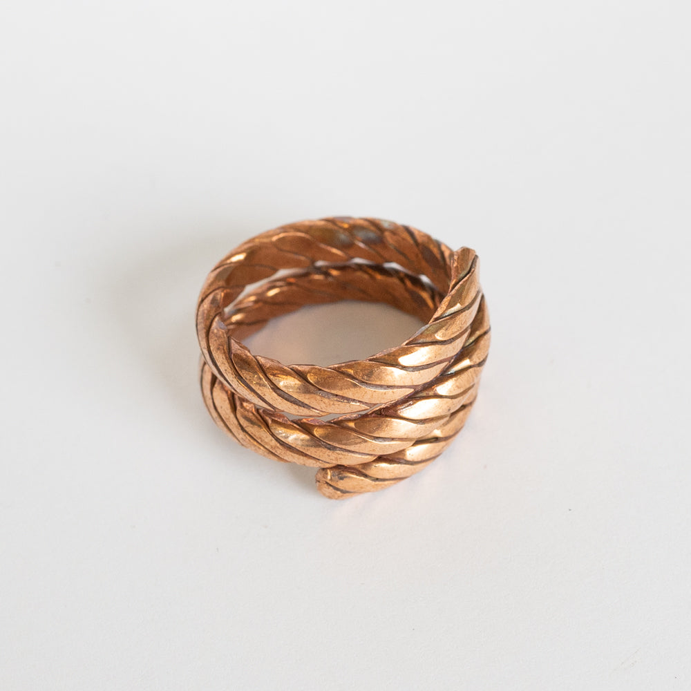 Copper twisted ring with a textured design on a white background