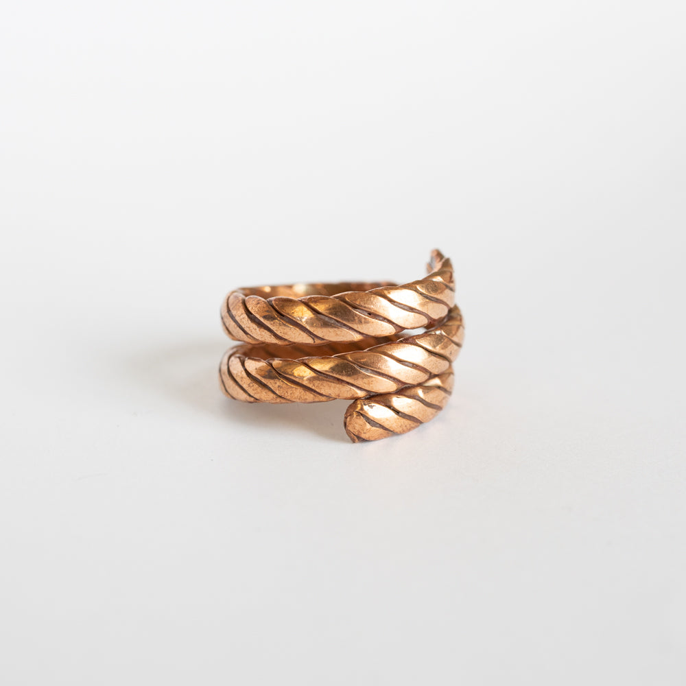 Copper ring with a textured design on a white background