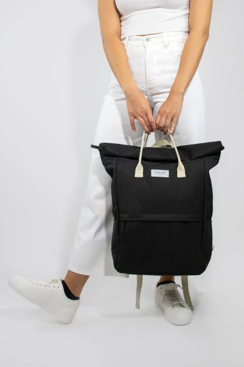 Person holding a black backpack with a white background