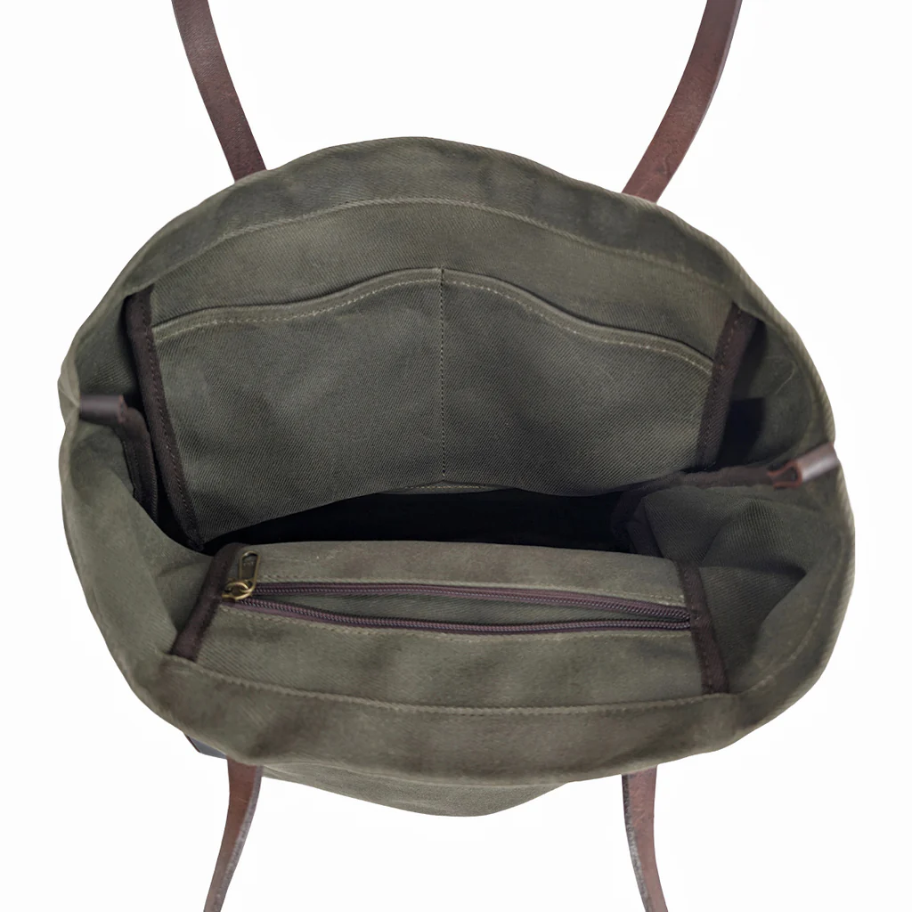 Green canvas tote bag with brown leather straps on a white background