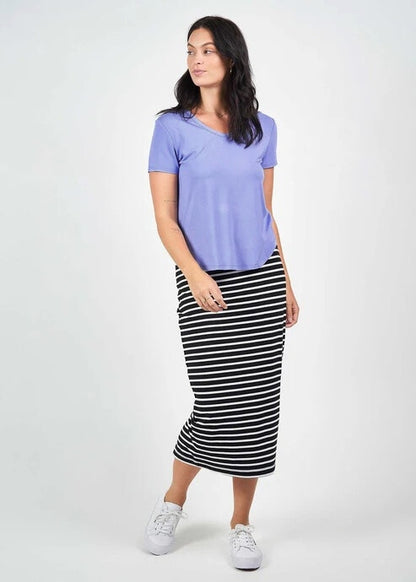 Woman wearing a purple shirt and black and white striped skirt on a white background