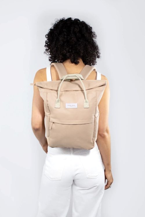 Person wearing a beige backpack against a white background