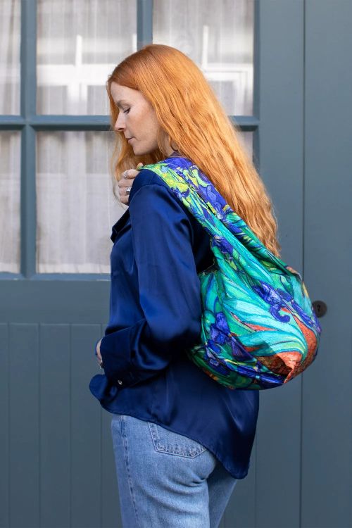 Person wearing a colourful reusable bag with a blue door in the background