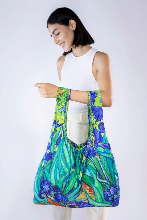 Woman holding a colourful bag with a Van Gogh floral painting on a white background