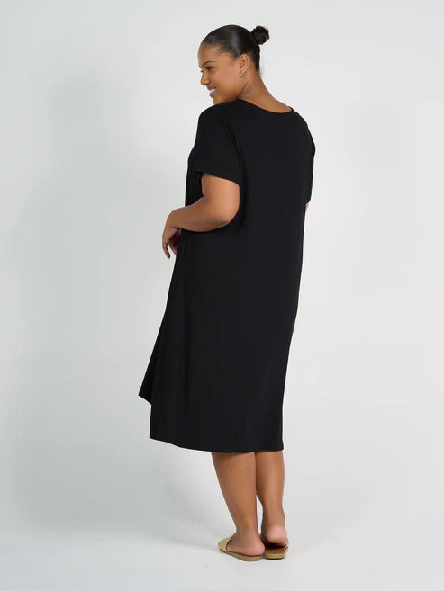 Woman wearing black bamboo knee length dress on white background.