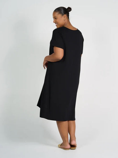 Woman wearing black bamboo knee length dress on white background.