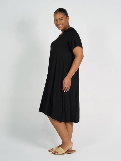 Woman wearing black bamboo knee length dress on white background.