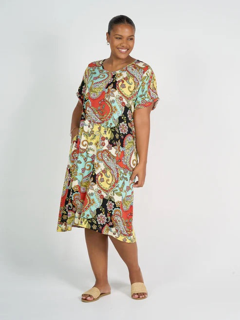 Woman wearing colourful patterned bamboo knee length dress on white background.