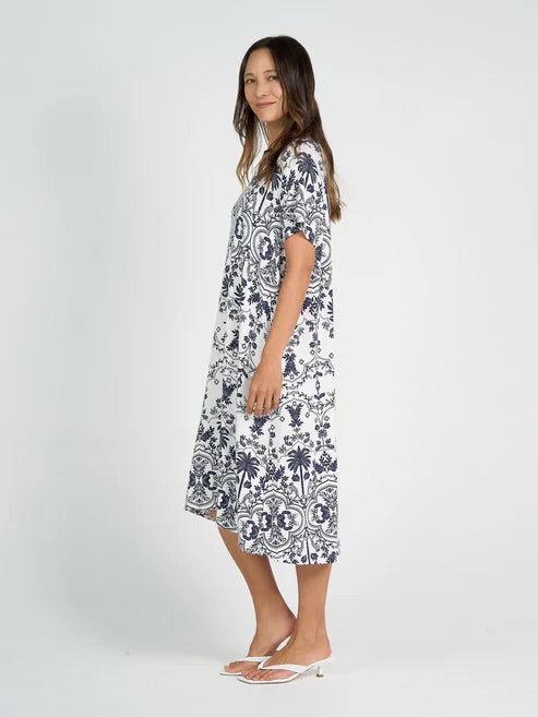 Woman wearing white and blue patterned bamboo knee length dress on white background.