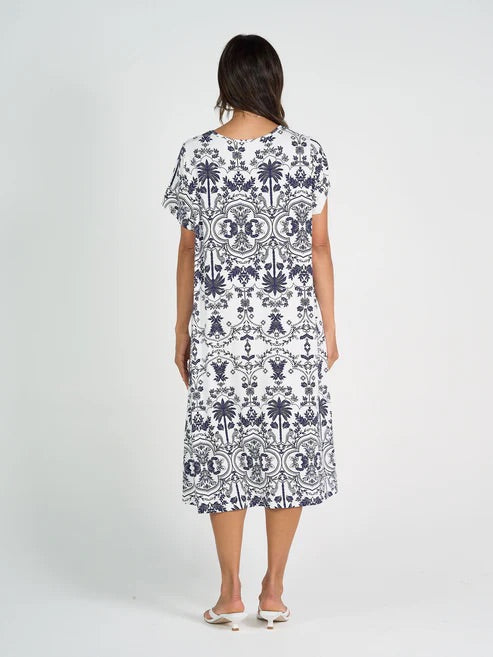 Woman wearing white and blue patterned bamboo knee length dress on white background.