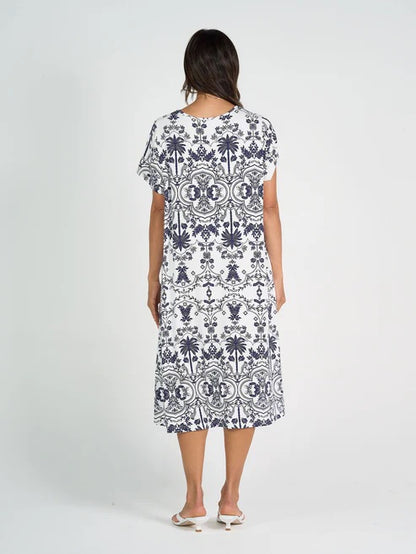 Woman wearing white and blue patterned bamboo knee length dress on white background.