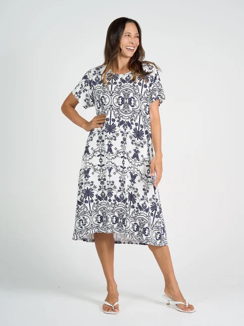 Woman wearing white and blue patterned bamboo knee length dress on white background.