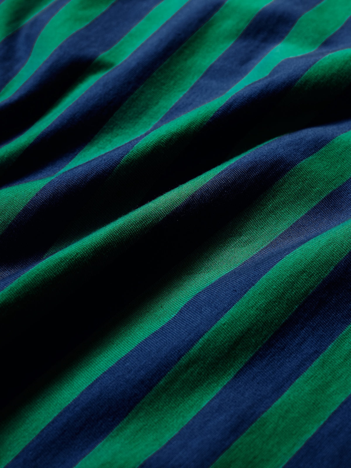A close-up of a striped fabric with alternating dark navy blue and bright green diagonal bands, showing the textile's texture and drape.