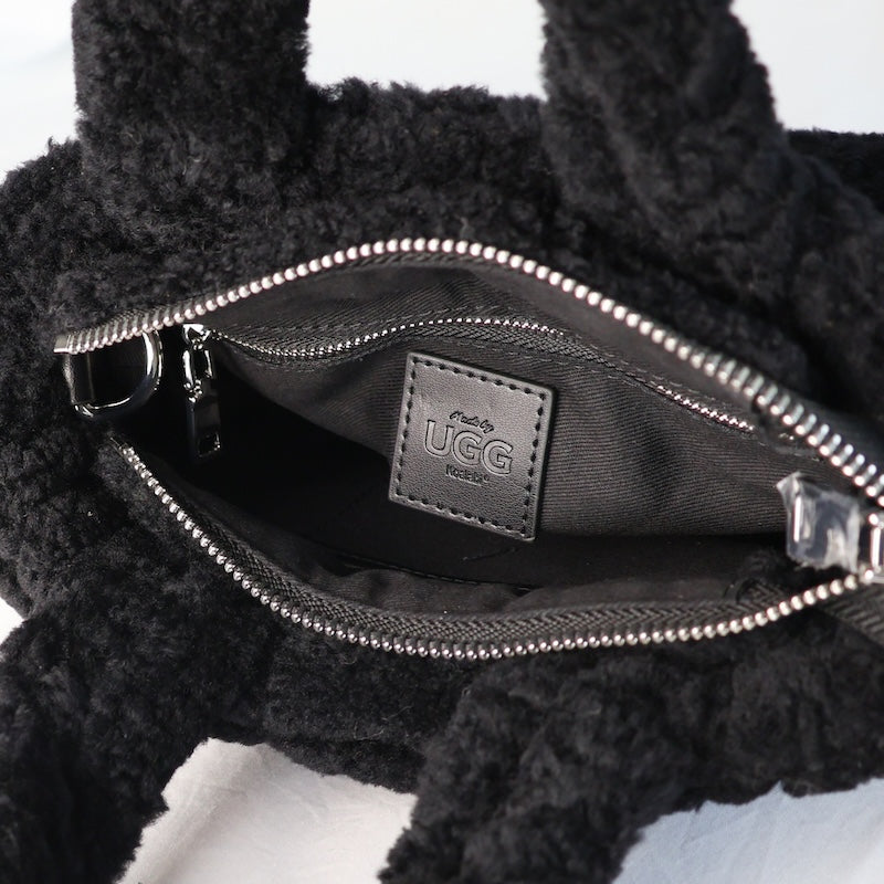 Black UGG bag with open zipper showing brand logo on a white background