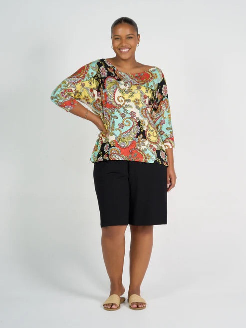 Woman wearing a colourful patterned top and long black bamboo shorts on a white background