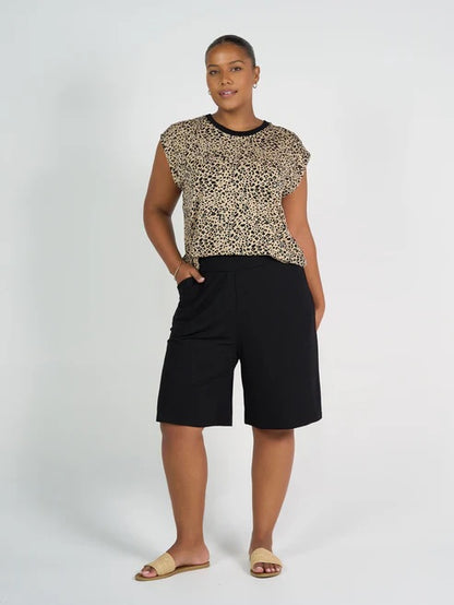 Woman wearing a leopard print top and long black bamboo shorts on a white background