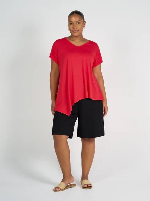 Woman wearing a red top and long black bamboo shorts on a white background