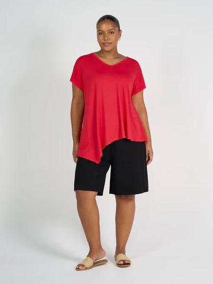 Woman wearing a red top and long black bamboo shorts on a white background