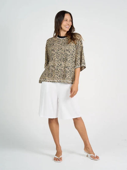 Woman wearing a leopard print bamboo top and white bamboo shorts on a white background