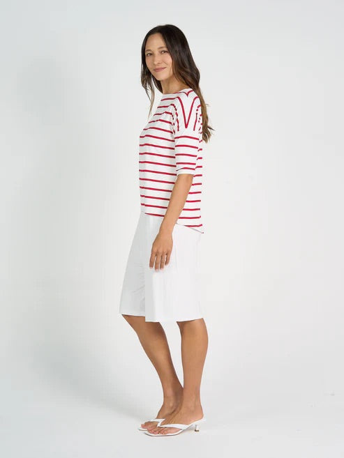 Woman wearing a red and white striped shirt with long white bamboo shorts on a white background