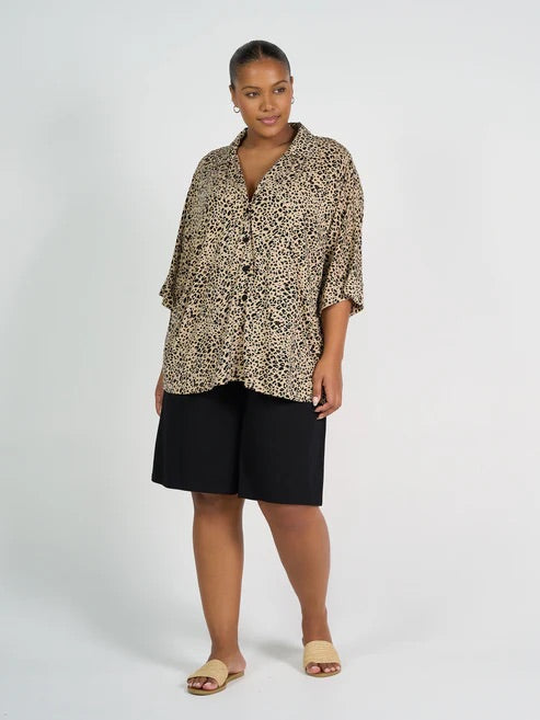 Woman wearing a leopard print shirt and long black bamboo shorts on a white background