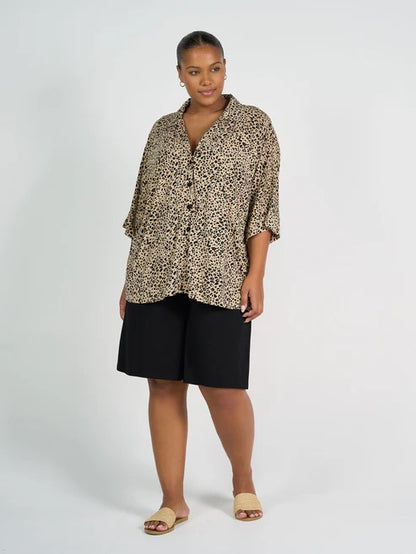 Woman wearing a leopard print shirt and long black bamboo shorts on a white background