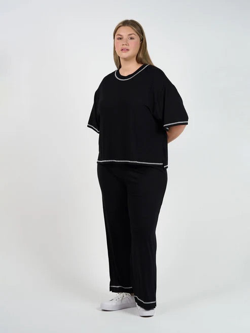 Person wearing a black bamboo shirt and pants with white trim on a white background