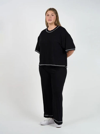 Person wearing a black bamboo shirt and pants with white trim on a white background