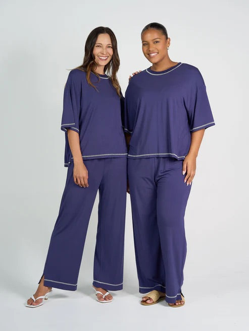 Two women wearing matching blue bamboo shirt and pants on a white background