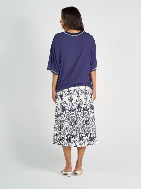 Woman wearing a navy bamboo top and white patterned skirt on a white background