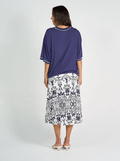 Woman wearing a navy bamboo top and white patterned skirt on a white background