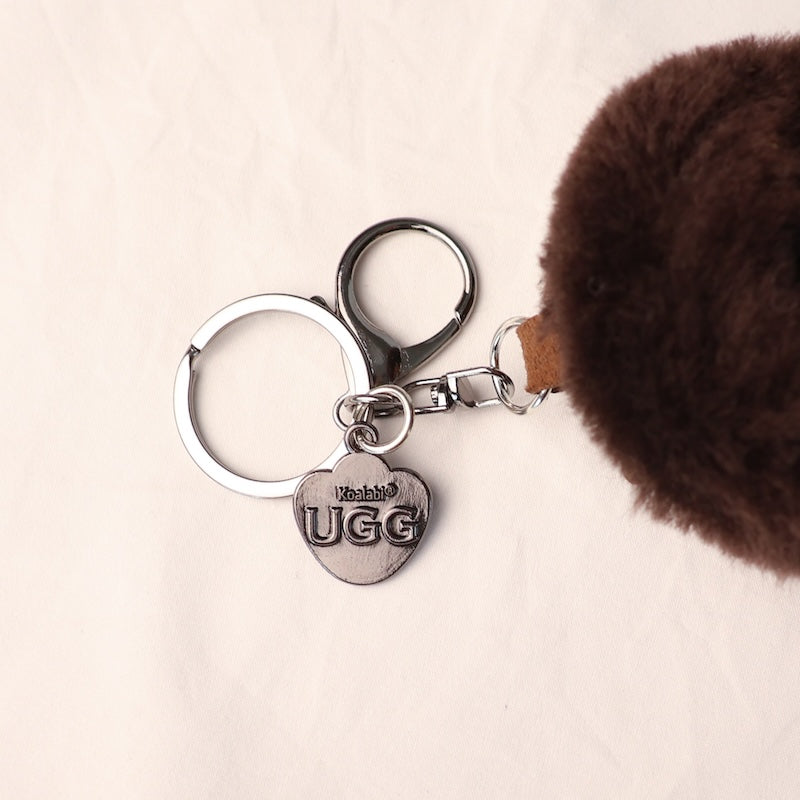 Keychain with UGG logo attached to a brown furry item on a light background