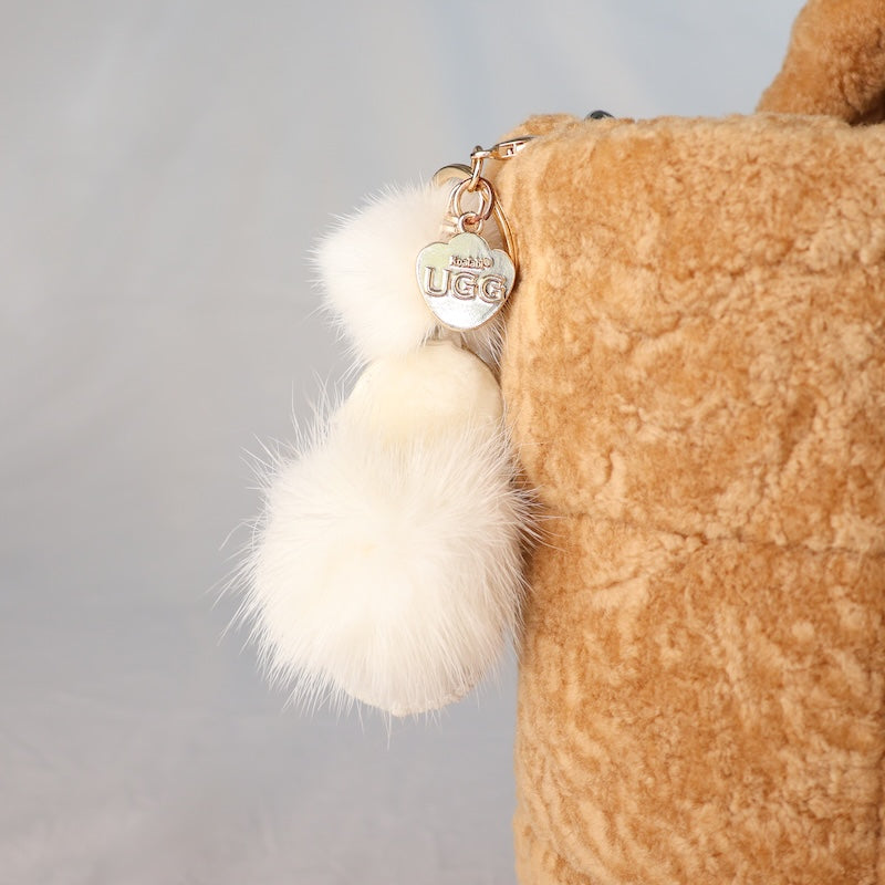Brown UGG mini scuff keychain with a fluffy pom-pom on a grey background