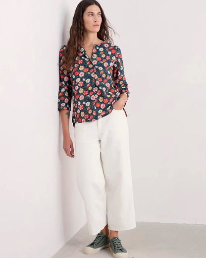 Woman wearing a floral blouse and white pants against a white background